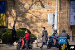 Seorang petugas keamanan berjaga saat orang-orang berjalan melewati Kedutaan Besar Kanada di Beijing, Kamis, 3 November 2022. (AP/Mark Schiefelbein)