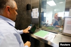 A man has his fingerprints electronically taken while taking part in a visa application demonstration