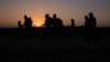 FILE - The sun rises as asylum-seeking migrant families from Honduras and El Salvador walk toward the border wall after crossing the Rio Grande into the United States from Mexico on a raft in Penitas, Texas, on March 26, 2021. 