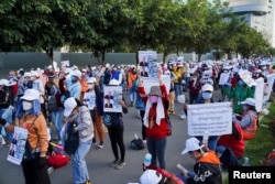FILE - NagaWorld casino workers hold up placards during a protest outside the National Assembly building after several union members were arrested, in Phnom Penh, Cambodia, Jan. 5, 2022.