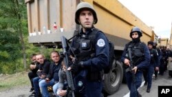 Pripadnici kosovske policije patroliraju između kamiona na mestu na kom su kosovski Srbi blokiraloi put, u blizini graničnig prelaza Jarinje, 20. septembra 2021. (Foto: AP/Bojan Slavković).