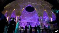 People walk near a lit up Al Wasl Dome at Expo City at the COP28 U.N. Climate Summit, Dubai, United Arab Emirates, Dec. 1, 2023.