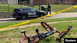 巴尔的摩一名警察走过枪击现场，路边有一辆儿童自行车。（2023年7月2日）