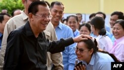 Member of parliament and Cambodia's former prime minister Hun Sen (L) greets commune councilors after he cast his vote at a polling station during the Senate election in Takhmao city, Kandal province on Feb. 25, 2024. 