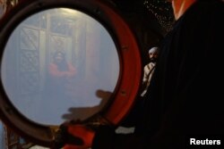 Seorang perempuan Palestina menonton penampilan kelompok Mesaharati, saat mereka membangunkan umat Islam untuk makan sahur pada bulan suci Ramadan, di Khan Younis, selatan Jalur Gaza 25 Maret 2023. (REUTERS/Ibraheem Abu Mustafa)