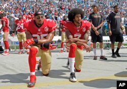 Erik Rid (levo) i Kolin Kepernik (desno) kleče tokom izvođenja američke himne na utakmici San Francisko Fortinajnersa i Karolina Pantersa (AP Photo/Mike McCarn)