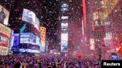 Orang-orang menyaksikan confetti beterbangan setelah jam menunjukkan tengah malam saat perayaan Tahun Baru di Times Square, di New York City, New York, AS, 1 Januari 2024. (Foto: REUTERS/Andrew Kelly)