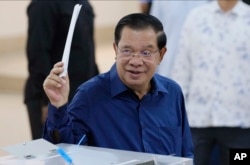 Cambodian Prime Minister Hun Sen of the Cambodian People's Party (CPP) raises a ballot before voting at a polling station at Takhmua in Kandal province, southeast Phnom Penh, Cambodia, July 23, 2023.