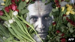 Flowers are seen placed around a portrait of the late Russian opposition leader Alexey Navalny at a makeshift memorial in front of the former Russian consulate in Frankfurt am Main, Germany, Feb. 19, 2024.