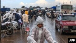 2024 年 2 月 2 日，以色列与哈马斯武装之间的战斗迫使许多加沙居民离开家园，他们聚集在加沙地带南部的汗尤尼斯。巴勒斯坦儿童穿着冠状病毒大流疫留下的防护服。