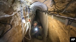 Seorang perwira militer Israel mengajak wartawan tur memasuki terowongan yang diduga digunakan oleh militan Palestina untuk serangan lintas batas, di Perbatasan Israel-Gaza pada 25 Juli 2014. (Foto: AP)