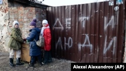 Beberapa anak tampak berkumpul di dekat sebuah rumah yang hancur di Mariupol, Ukraina, pada 25 Februari 2023. (Foto: AP/Alexei Alexandrov)