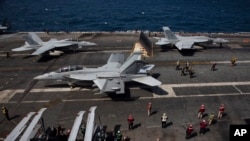 F-18 Super Hornet Angkatan Laut AS dan kru terlihat di dek penerbangan kapal induk bertenaga nuklir USS Nimitz di lepas pantai Busan, Korea Selatan, Senin, 27 Maret 2023. (Jeon Heon-kyun/Pool Foto via AP)