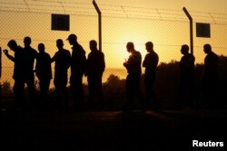 Pekerja Palestina berjalan di dekat pagar saat matahari terbit untuk memasuki penyeberangan Erez ke Israel, setelah Israel mengakhiri larangan pekerja dari Gaza dan penyeberangan dibuka kembali di Kota Gaza 28 September 2023. (REUTERS/Ibraheem Abu Mustafa)