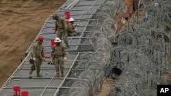 Guardsmen fortify the border along the Rio Grande with concertina wire, Feb. 2, 2024, in Eagle Pass, Texas.