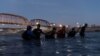 FILE - Migrants link arms with each other as they wade into the Rio Grande River with intentions to cross into Eagle Pass, Texas, U.S., in Piedras Negras, Coahuila, Mexico, Feb. 24, 2024. 