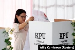 Seorang perempuan sedang mencoblos di sebuah TPS di Solo, Jawa Tengah, Rabu, 14 Februari 2024. (Foto: Willy Kurniawan/Reuters)