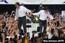 Calon presiden dan wakil presiden, Anies Baswedan (kiri) dan Muhaimin Iskandar, menyapa pendukungnya saat kampanye di Jakarta International Stadium, Jakarta pada 10 Februari 2024. (Foto: AFP/Bay Ismoyo)