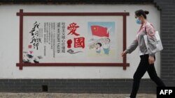 一名女子走过北京街头的一面中国政府宣传社会主义核心价值观的宣传墙。（2021年6月9日）