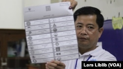 មន្ត្រីរៀបចំការបោះឆ្នោត ក្នុងមណ្ឌលមួយក្នុងរាជធានីភ្នំពេញ លើកបង្ហាញ​សន្លឹកឆ្នោត​ដែល​ត្រូវ​​បាន​គូស​ចោល និងរាប់ នៅថ្ងៃទី២៣ ខែមិថុនា ឆ្នាំ២០២៣។ (លាស់ លីបលីប/វីអូអេ)