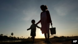 រូបឯកសារ៖ ស្ត្រីមានផ្ទៃពោះនិងកូនដើរកាត់ក្នុងភូមិមួយ នៅជាយរាជធានីភ្នំពេញ កាលពីថ្ងៃទី៤ ខែមករា ឆ្នាំ២០១៨។