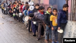 Anak-anak Palestina membawa panci saat antre untuk menerima pembagian makanan dari sebuah dapur amal, di tengah kekurangan pasokan makanan di Rafah, Jalur Gaza selatan (foto: dok). 