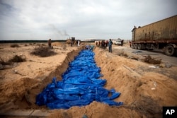 Palestinians bury people killed in the Israeli bombardment who were brought from the Shifa hospital, in a mass grave in the town of Khan Younis, southern Gaza Strip, Nov. 22, 2023.
