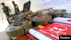 Anggota militer Kamboja berdiri di dekat berbagai jenis ranjau darat dan roket yang dipamerkan di Provinsi Kampong Speu, 27 November 2011. (Foto: Reuters)