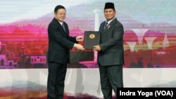 Menteri Pertahanan Prabowo Subianto (kiri) menyerahkan Jakarta Joint Declaration of The ASEAN Defence Ministers Meeting kepada Sekretaris Jenderal ASEAN, Kao Kim Hourn (kanan), Rabu, 15 November 2023, di Jakarta. (Foto: Indra Yoga/VOA)