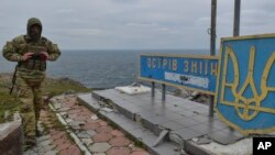 Seorang tentara Ukraina melewati papan penanda yang bertuliskan "Pulau Ular milik kami" di Pulau Ular, Laut Hitam, Ukraina, 18 Desember 2022. (Foto: Michael Shtekel/AP Photo)