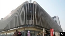 FILE — Residents walk past an Evergrande commercial complex in Beijing, Jan. 29, 2024. In a report released Friday, the International Monetary Fund projects China's economic growth will drop to 4.6% this year, down from 5.2% growth last year.