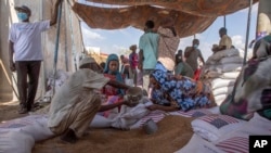 FILE - Refugees collect food rations from the U.S. Agency for International Development at a distribution point in eastern Sudan, March 24, 2021. USAID says it may need to cut its response to global crises because of U.S. budget cuts. 