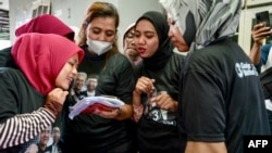 Para perempuan mengenakan kaos bergambar pasangan capres-cawapres Ganjar Pranowo-Mahfud MD, sedang menonton tarian TikTok mereka yang digunakan oleh Ukon Furkon Sukanda, calon anggota legislatif dari PDI-P di Tangerang, Banten, 10 Januari 2024. (BAY ISMOYO/AFP)