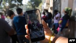 Seorang migran pengguna TikTok migran melihat saran dari migran pengguna lainnya, sebelum bergerak menuju perbatasan AS di luar Komisi Bantuan Pengungsi Meksiko (COMAR) di Mexico City, 14 Maret 2023. (CLAUDIO CRUZ/AFP)