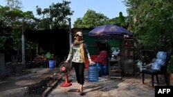 FILE - Resident Chea Srey Sar carries her belongings to a military truck at the Angkor Wat temple area in Siem Reap province, Cambodia, Jan. 16, 2023.