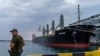 FILE - A security officer stands next to the ship Navi-Star loaded with grain as it waits to sail to sail from the Odesa Sea Port, in Odesa, Ukraine, on July 29, 2022.