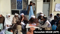 FILE - Afghan refugees deported from Pakistan wait to receive food aid by the Red Cross Society in Kandahar, Afghanistan, on Jan. 24, 2024.