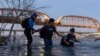 Seorang perempuan dari Guatemala (kiri) bersama migran lainnya menyeberangi sungai Rio Grande dari Piedras Negras di Meksiko untuk mencapai Eagle Pass, Texas, pada 24 Februari 2024. (Foto: Reuters/Cheney Orr)