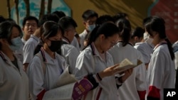 北京的中学生在进入高考考场前温习功课。（2023年6月7日）