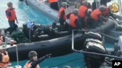 In this handout photo provided by Armed Forces of the Philippines, Chinese Coast Guard hold knives and machetes as they approach Philippine troops on a resupply mission in the Second Thomas Shoal at the disputed South China Sea on June 17, 2024. 