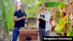 ອາຈານແສງອາລຸນ ແລະແຂກຕ່າງປະເທດ ທີ່ມາຢ້ຽມຢາມ ແລະຖອດຖອນບົດຮຽນ ຈາກການລ້ຽງເຜິ້ງທໍາມະຊາດ ໃນຟາມລ້ຽງເຜິ້ງ ບ້ານນາຊູ, ເມືອງໂພນໂຮງ, ແຂວງວຽງຈັນ.