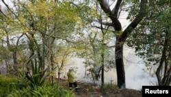 Petugas pemadam kebaran mengamati kerusakan yang ditimbulkan dari kebakaran hutan yang terjadi di kawasan Sydney, Australia, 10 September 2023. (Foto: Reuters/Cordelia Hsu) 