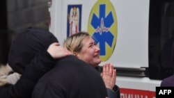 Local residents react outside a building damaged by a missile attack in Kyiv, Ukraine, Feb. 7, 2024.