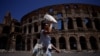 Seorang turis tampak melindungi wajahnya dari sinar matahari dengan kipas yang ia bawa saat berkunjung ke Colosseum di tengah gelombang panas yang menyerang Roma, pada 11 Juli 2023. (Foto: Reuters/Guglielmo Mangiapne)