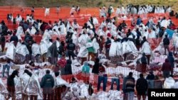 Para migran tampak mengenakan selimut dari mylar untuk menjaga tubuh mereka tetap hangat ketika berada di luar pusat pemrosesan migran di Eagle Pass, Texas, pada 20 Desember 2023. (Foto: Reuters/Cheney Orr)