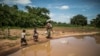 A family walks home after collecting food from a distribution organized by the World Food Program and World Vision in Simumbwe, Zambia, Jan. 22, 2020. Four years later, the country is experiencing a severe drought threatening national food security. 