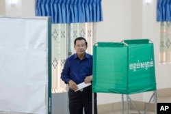 Cambodian Prime Minister Hun Sen, of the Cambodian People's Party (CPP), stands behind a screen before voting a ballot at a polling station in Takhmua in Kandal province, southeast Phnom Penh, Cambodia, July 23, 2023.