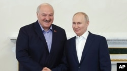 Presiden Rusia Vladimir Putin (kanan) menjabat tangan Presiden Belarus, Alexander Lukashenko, dalam pertemuan di St. Petersburg, Rusia, pada 23 Juli 2023. (Foto: Alexander Demianchuk, Sputnik, Kremlin pool via AP)