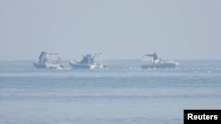 FILE - China Coast Guard boats are close to a floating barrier on Sept. 20, 2023, near the Scarborough Shoal in the South China Sea. (Philippine Coast Guard via Reuters)