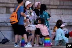 前来北京参观故宫的游客手持小电扇在阴凉地里排队等候入门。（2023年7月7日）